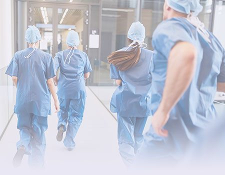 Four emergency room nurses in blue scrubs running towards ER representing Emergency Nursing CEUs