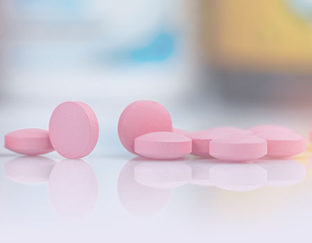 Eight pink pills laying on table representing pharmacology nursing CEU credits for APRN/ARPN and nurse practitioner