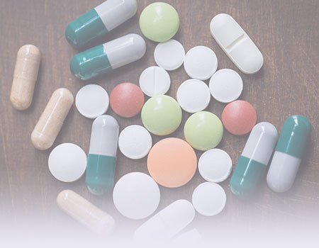 A variety of different shaped and colored pills laying on a table representing substance abuse and addiction nursing CEU