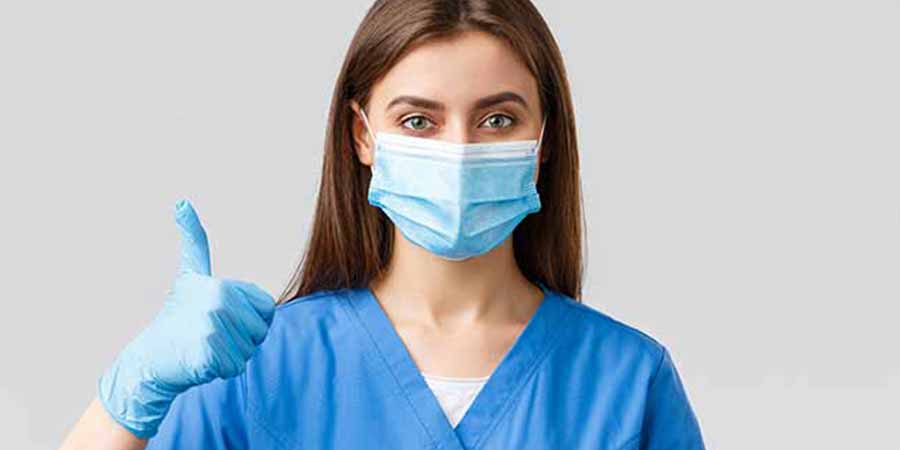 Masked nurse gives a thumbs up.