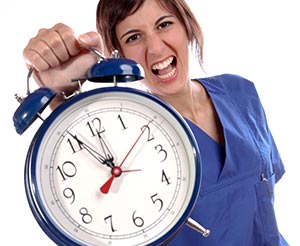 Nurse in scrubs holding blue alarm clock to signal last-minute rush