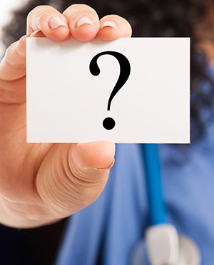 Nurse holding up a card with a question mark on it