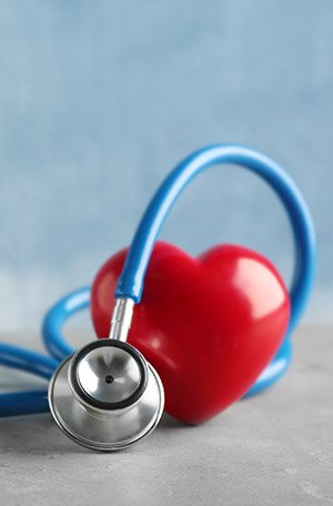 Photography of a stethoscope wrapped around a plastic heart.