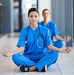 Nurse meditating with her fellow workers.