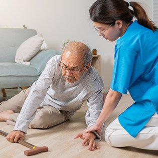 Nurse helping her fallen patient off the ground.