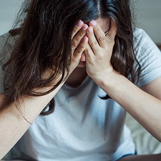 Lady holding her head in her hands.