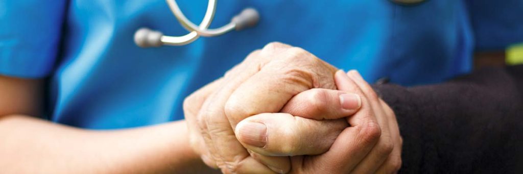 Nurse holding hands with her patient.