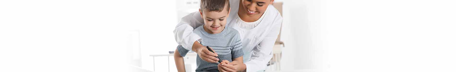 Woman in white shirt hugging young boy from the back and pricking his finger for childhood diabetes testing