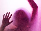 Shadow outline of female torso in purple with raised arms and hands for human trafficking protection