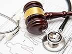 Dark wood and golden gavel and black stethoscope laying on medical error reporting form