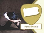 Young abused child sitting on floor with face burried in their knees and arms holding knees and Pennsylvania state outline
