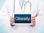 Healthcare professional in white coat with stethoscope around neck holding a blue sign with obesity written on it 