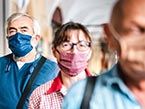 Three adults standing behind each other with blue and red face masks to protect them from the COVID-19 virus infection