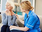 Nurse in blue scrubs putting her hand on elderly female patient with mental illness