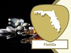 Various prescription pills causing impairment laying on black surface and Florida state outline