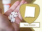 Left hand holding 8 oval shaped white prescription pain management pills and New Mexico state outline