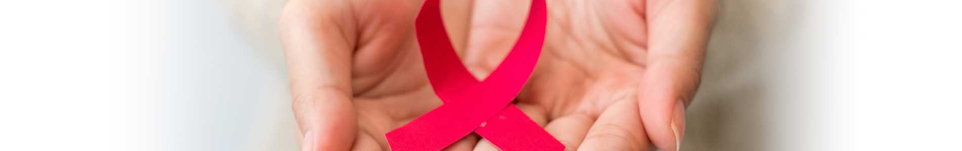 Two hands pointing towards viewer, holding red ribbon representing HIV/AIDS prevention