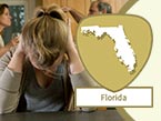 Woman's head with blond ponytail clutching her hands on her neck for stress from domestic violence and Florida state outline