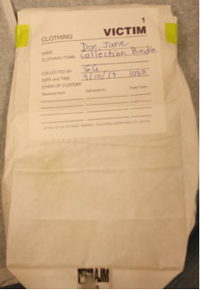 Forensic examination clothing collection photo showing sealed and labeled evidence bag.