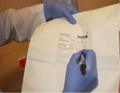 Forensic examination clothing collection photo showing nurse labeling evidence bag.