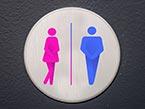Gray circle with a pink female and blue male icon inside, both crossing their legs tightly representing urinary incontinence