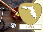 Dark wood and golden gavel and black stethoscope laying on wooden surface and Florida state outline