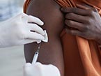 Two hands in white medical gloves giving a respiratory virus vaccine for flu, COVID-19, RSV or pneumococcal in a patient's arm with a syringe.