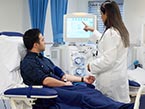 Male patient receiving treatment from a dialysis machine and listening to a nurse discussing his chronic kidney disease.