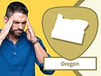 Male nurse with beard in blue scrubs holding his temples with his hands to manage pain and Oregon state outline
