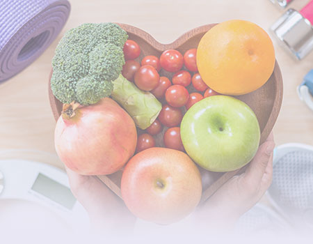 Fruits and vegetables in a heart shaped wooden bowl with excersize mat for nutrition and weight management nursing CEUs